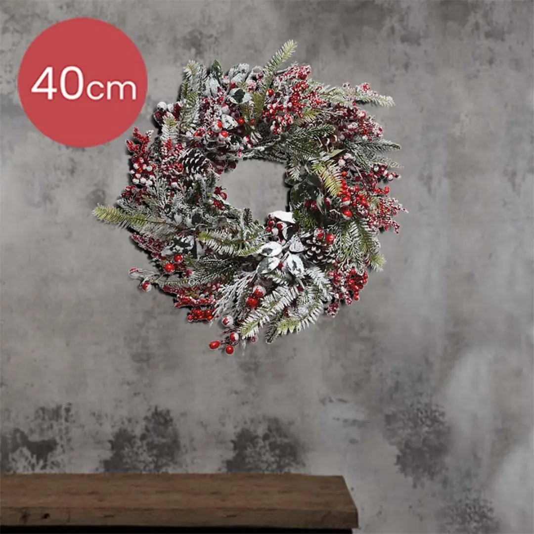 Decoratieve kerstkrans met sneeuw en rode besjes
